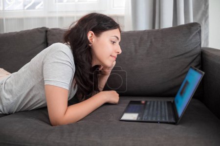 Jeune adolescente bavarder avec des amis en ligne sur ordinateur portable