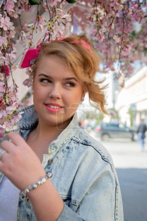 Téléchargez les photos : Portrait d'une grosse fille en vacances au printemps dans une belle rue en plein air entourée de fleurs. - en image libre de droit