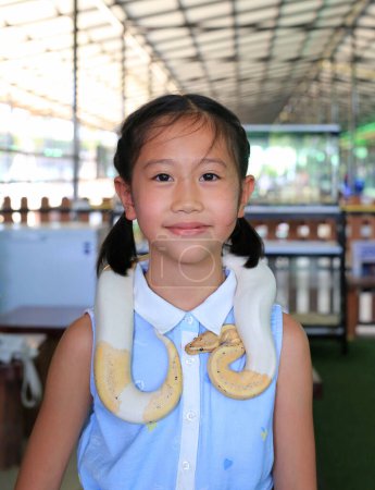 Asian girl child with pet snake or royal albino python (Boa constrictor snake).