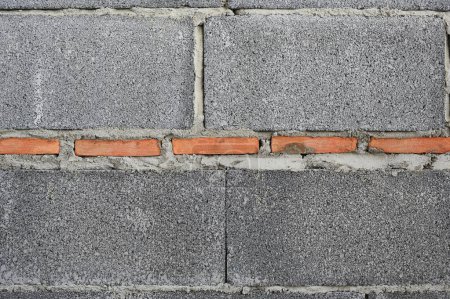 Téléchargez les photos : Nouveau bloc de briques de béton fond texture murale avec brique rouge au centre. - en image libre de droit