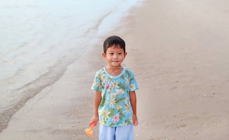 Téléchargez les photos : Portrait de sourire asiatique petit garçon sur la plage de sable. - en image libre de droit