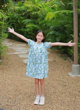 Téléchargez les photos : Jolie asiatique fille bras tendus ou garder les bras levés tout en se tenant dans le jardin. - en image libre de droit