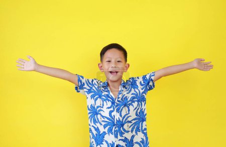 Téléchargez les photos : Portrait de garçon asiatique heureux enfant en costume d'été bras levés ou mains ouvertes geste large isolé sur fond jaune. - en image libre de droit