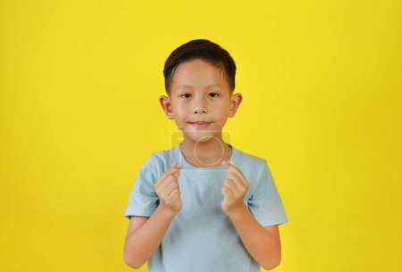 Téléchargez les photos : Asiatique garçon enfant montrer doigt mini coeur symbole langue des signes isolé sur jaune studio fond. - en image libre de droit