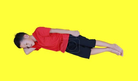 Téléchargez les photos : Sommeil garçon asiatique avec bras soutenir sa tête isolée sur fond jaune. Longueur totale. - en image libre de droit