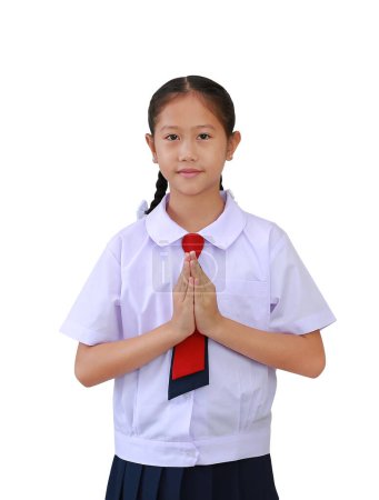 Estudiante asiática en uniforme de escuela primaria o primaria de pie con respeto Pagar o rezar postura aislada sobre fondo blanco. Vista frontal de la imagen con ruta de recorte.