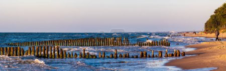 Photo for Mielno, Poland - Jun, 2022: Sunset over the Baltic Sea. View of the old wooden breakwater and its reflection in the water.  West Pomeranian. eastern Europe - Royalty Free Image