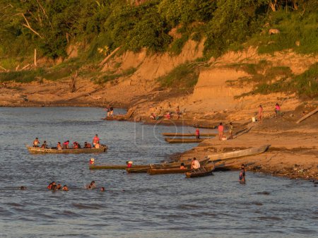 Téléchargez les photos : Amazone, Pérou - 24 sept. 2018 : Population locale sur la rive de l'Amazone pendant la basse saison des eaux. Coucher de soleil depuis le pont d'un cargo Amazonie. Pérou. Amérique du Sud. - en image libre de droit
