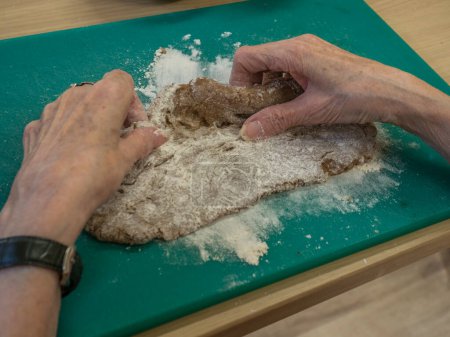 Foto de Mujer anciana amasando masa y preparando galletas de Navidad - Imagen libre de derechos