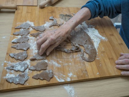Foto de Mujer anciana amasando masa y preparando galletas de Navidad - Imagen libre de derechos