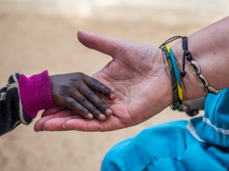 Téléchargez les photos : Un enfant africain touche la main d'une femme blanche. Concept de diversité. Sénégal. Afrique. - en image libre de droit