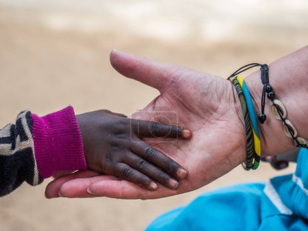 Téléchargez les photos : Un enfant africain touche la main d'une femme blanche. Concept de diversité. Sénégal. Afrique. - en image libre de droit