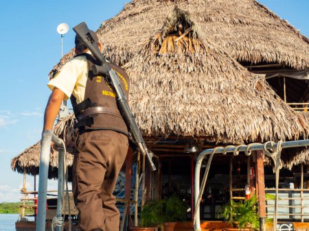 Foto de Iquitos, Perú - Diciembre 2017: Guardaespaldas con un arma en un barco que va a un restaurante de lujo en el río Amazonas. Amazonia. América Latina - Imagen libre de derechos