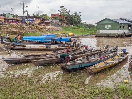 Photo for Tabatinga, Brazil - November 25, 2018: People and wooden boat in  the port of Amazon river. South America. Amazon River.  Tres fronteras. Rain Forest of Amazonia. - Royalty Free Image