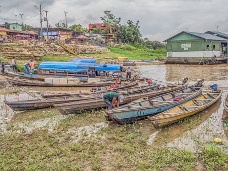 Photo for Tabatinga, Brazil - November 25, 2018: People and wooden boat in  the port of Amazon river. South America. Amazon River.  Tres fronteras. Rain Forest of Amazonia. - Royalty Free Image