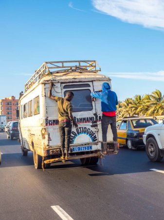 Téléchargez les photos : Dakar, Sénégal - 2 février 2019 : La vie quotidienne au Sénégal. Vieux microbus encerclant les routes, avec les passagers sur la porte arrière. Dakar, Sénégal. Afrique. - en image libre de droit