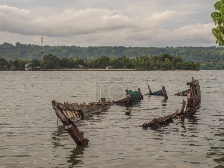 Photo for Wreck of wooden boat laying on the coast of the island of Ambon in Indonesia. Ambon Island, Central Maluku, Indonesia - Royalty Free Image
