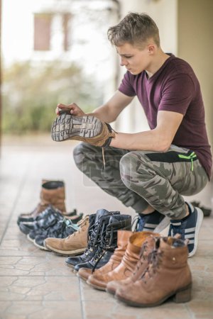 Téléchargez les photos : Jeune homme est le polissage des chaussures sur la terrasse pendant le printemps - en image libre de droit