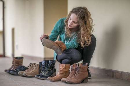 Téléchargez les photos : Jeune femme est le polissage des chaussures sur la terrasse pendant le printemps - en image libre de droit