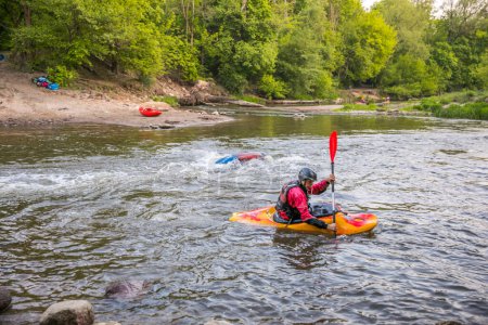 Photo for Jozefow, Poland - May  12: Water canoeing, extreme kayaking. Kayakers  in a small sport kayaks are practicing  an approach to a cascade on the Swider River in Poland - Royalty Free Image