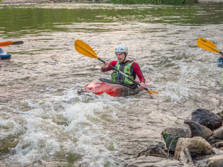 Photo for Jozefow, Poland - May  12: Water canoeing, extreme kayaking. The guy in a small sport kayak practices an approach to a cascade on the Swider River in Poland - Royalty Free Image