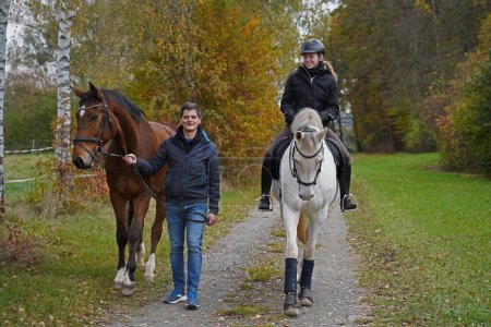 Foto de Shooting with brown Rhineland gelding, white mare, her rider and friend - Imagen libre de derechos