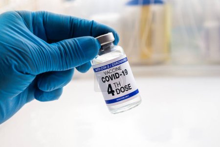 Téléchargez les photos : COVID-19 Vaccin Flacon pour vaccination étiqueté avec la 4e dose. médecin avec flacon de vaccin contre le coronavirus portant le nom du quatrième vaccin sur l "étiquette - en image libre de droit