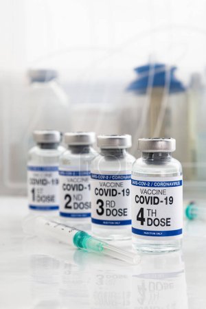 Foto de COVID-19 viales de vacuna para la vacunación etiquetados como 1ª, 2ª, 3ª y 4ª dosis para la inyección de refuerzo para la variante omicrónica. Vacuna contra el Coronavirus etiquetada como primera, segunda, tercera y cuarta dosis de vacuna en la etiqueta - Imagen libre de derechos