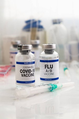Foto de Frascos de vacuna contra el Coronavirus y vacuna antigripal para la vacunación de recuerdo de nuevas variantes del virus Sars-cov-2 y la gripe A. Viales de vacuna contra la gripe A-B y Covid-19 para la inyección de refuerzo para el virus de la influenza y el omicrón - Imagen libre de derechos