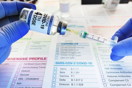 Foto de Jeringa y vial de vacuna contra el coronavirus etiquetados con la cuarta dosis en la etiqueta para la vacunación de pacientes. manos de un médico dosificando en la jeringa la dosis de la cuarta dosis de la vacuna COVID-19 - Imagen libre de derechos