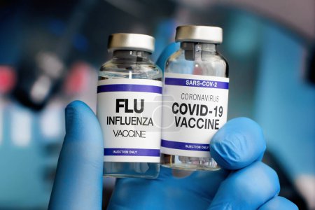 Foto de Vacuna contra la gripe y el virus Covid-19 para el refuerzo del omicrón y la gripe. Viales de vacuna contra el Coronavirus y vacuna antigripal para la vacunación de recuerdo de nuevas variantes del virus Sars-cov-2 y la gripe - Imagen libre de derechos
