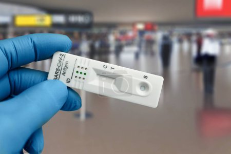 Airport checkpoint worker with covid or Coronavirus antigen diagnostic test device for diagnostic in tourists. doctor holding COVID-19 or sars-cov-2 virus disease rapid swab test to travelers on international airport