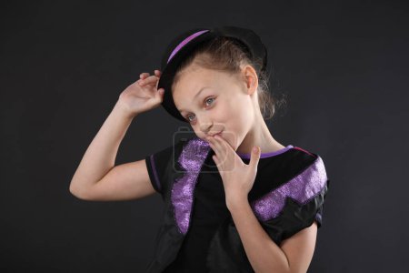 Foto de Retrato de una chica feliz en el estudio sobre un fondo negro, vestido con una camiseta y sombrero negro, sonriendo. - Imagen libre de derechos