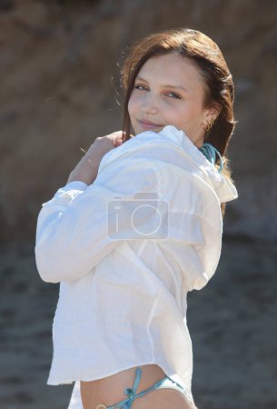 Foto de Sonriente bonita joven en camisa blanca en la playa - Imagen libre de derechos
