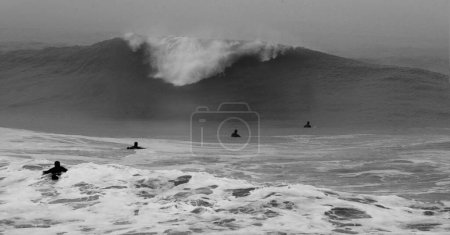 Photo for Surfers facing the wave  in the stormy ocean - Royalty Free Image