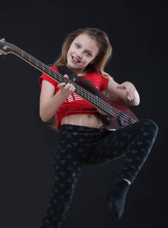 Photo for Little girl with a bass guitar. the girl plays a musical instrument. - Royalty Free Image