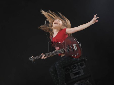 Foto de Chica joven tocando la guitarra sobre un fondo oscuro. - Imagen libre de derechos