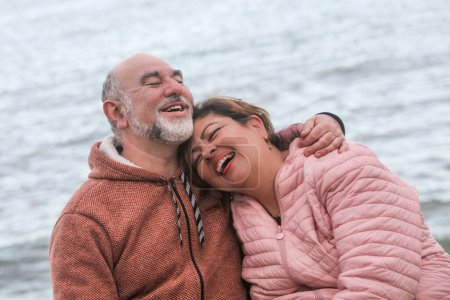 Photo for Mature couple laughing and hugging by the ocean - Royalty Free Image