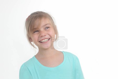 Porträt eines fröhlichen kleinen Mädchens, das seitwärts schaut, um Raum auf weißem Hintergrund zu kopieren