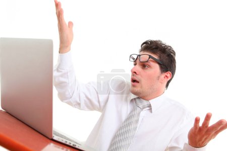 stressed out man with glasses on white background looking at laptop screen in despair 