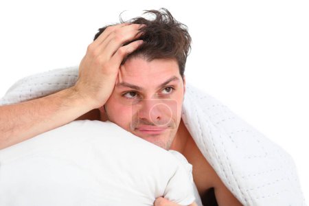 close up portrait of frustrated upset young man in bed on white background