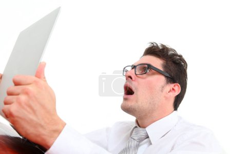 stressed out man with glasses on white background looking at laptop screen in despair 