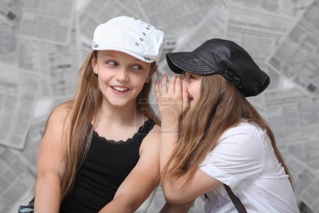 Photo for Two cute stylish preteen girls gossiping over background with newspapers - Royalty Free Image