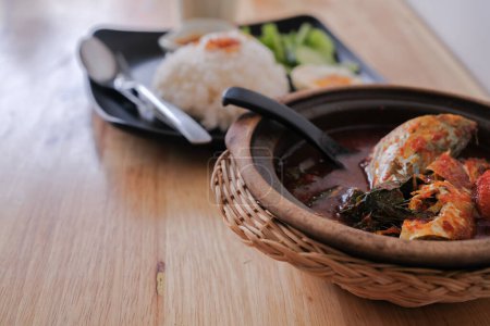 Téléchargez les photos : Une photo d'Ikan Kembung "asam pedas" avec du riz blanc sur un fond en bois. "Asam pedas" est une soupe aigre à base de tamarin, de piment et d'épices qui est populaire en Malaisie - en image libre de droit