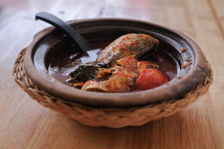 Une photo d'Ikan Kembung "asam pedas" avec du riz blanc sur un fond en bois. "Asam pedas" est une soupe aigre à base de tamarin, de piment et d'épices qui est populaire en Malaisie