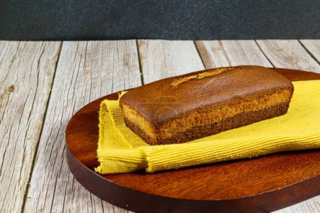 Téléchargez les photos : Un gâteau anglais dans un plat de cuisson sur une planche en bois et une table en bois blanc. Concentration sélective - en image libre de droit