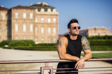 bel homme musclé avec tatouage posant dans le jardin de luxe européen au palais royal Venaria Reale près de Turin, Italie