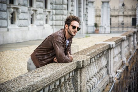 Téléchargez les photos : Attrayant jeune homme en veste de cuir en plein air, en ville européenne, Turin en Italie - en image libre de droit