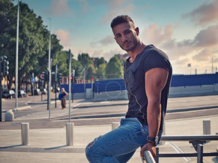 Téléchargez les photos : Un beau jeune homme en milieu urbain dans la ville européenne, portant un jean et un t-shirt noir - en image libre de droit