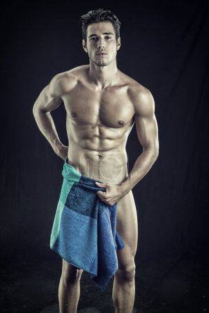 Porträt eines nackten, gut aussehenden jungen Mannes mit schmachtendem Blick, der den Schritt mit einem Handtuch oder T-Shirt bedeckt